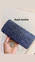 Clutch de fiesta en color azul noche con textura de rayas, sostenido en una mano.