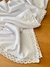 Mantel blanco con puntillas, elegante y suave, sobre una mesa de madera.