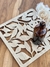 Posafuente de madera con diseño de hojas, decorado con una botella marrón y flores secas sobre una mesa de madera.