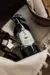 Aromatizador en spray para telas de la marca Aurea, presentado en un frasco oscuro con una etiqueta decorativa y rodeado de elementos de decoración.