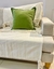 Sillón Kansas Gris con cojín verde sobre una manta clara, decorando un ambiente moderno.