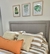 Respaldo de cama nórdico en un dormitorio con almohadas decorativas y cuadros de plantas en la pared.