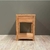 Mesa de luz de madera con un diseño sencillo, con un cajón y un estante inferior, ubicada frente a una pared verde.