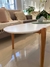 Mesa ovalada baja de color blanco con patas de madera, situada en un ambiente moderno y acogedor.