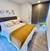 Acolchado king blanco en una cama con sábanas amarillas y decoraciones modernas en una habitación iluminada.