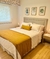 Habitación decorada con un cubrecama 1 1/2 plaza de color blanco y una manta amarilla, con cuadros de hojas en la pared.