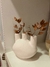Candelabro África de cerámica blanca con ramas secas en un estante.