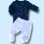 Conjunto de bebê com camiseta de manga longa azul marinho estampada com cães bombeiros e calça branca.