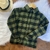 Camisa xadrez infantil flanelada em verde musgo, com detalhes em preto e botões frontais.