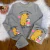 Conjunto infantil cinza de moletom pelúciado com estampa de capivara segurando copo rosa, composto por blusa e calça