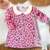 Vestido infantil flanelado rosa chiclete com estampa de corações em diversas cores.