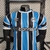 A camisa titular do Grêmio para a temporada traz as inconfundíveis faixas verticais em azul celeste e preto separadas por linhas brancas.A gola é branca com bordas celestes, enquanto os ombros ganha a cor preta, que aparece acompanhada de bordas brancas, 