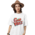 Mulher usando uma camiseta branca estampada com "Good Vibes" em cores vibrantes.