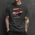 Camiseta preta com estampa do carro Chevrolet Omega CD 1997 em destaque, usada por homem com tatuagens nos braços