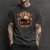 Camiseta preta unissex com estampa vintage de capacete de motoqueiro e óculos, texto "Born to Ride" e detalhes em vermelho e bege