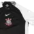 Camisa do Corinthians Away 25/26, predominantemente preta com mangas brancas e logo do time em destaque.