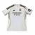 Camisa Home do Real Madrid 25/26, predominantemente branca, com detalhes em amarelo e logo da Adidas.