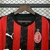 Camisa do AC Milan da temporada 25/26, com design listrado em vermelho e preto, logotipo da Emirates e da Puma.