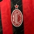 Camisa do AC Milan da temporada 25/26, com design listrado em vermelho e preto, logotipo da Emirates e da Puma.