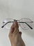 Anteojos de receta Karün Turkey sostenidos por una mano, con montura plateada y lentes transparentes.