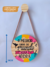 Quadro Decorativo de pinus redondo de 18 cm pendurada na parede com gancho redondo de pinus, escrito: O melhor lugar do mundo é aqui  e agora, feita a mão, com acabamento de tira de couro
