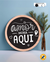 Placa de pinus redonda de 18 centímetros decorando a mesa personalizada, escrito: O amor mora aqui, feita a mão, a placa esta na parede.
