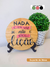 Placa de pinus redonda de 18 centímetros decorando a mesa, escrito Nada é em vão se não é benção é lição, feita a mão, com acabamento de suporte de mesa