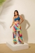 Modelo usando calça leque colorida em tons vibrantes, combinada com top azul, em fundo claro.