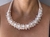 Conjunto de colar e brincos encapados com fio e bordados com perolas e miçangas na cor creme.
