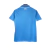 Camisa titular Napoli 2024-2025 azul celeste com mosaico de escudos em embossing. Gola pólo azul com contorno branco e punhos brancos. Nome do time na nuca. Escudo branco no peito esquerdo, logo EA7 branco no direito.