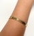 Bracelete dourado de metal com linhas