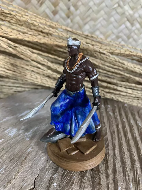 Estátua em miniatura do Orixá Ogum, representando um guerreiro com espadas e vestimenta azul, feita de resina.