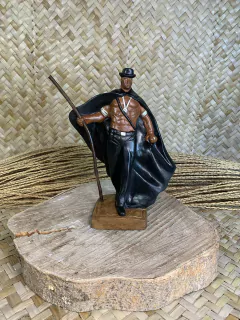 Estátua personalizada de Exú Lobo Preto, representando uma figura masculina com capa e chapéu, segurando um bastão, sobre uma base de madeira.