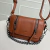 Bolsa pequena de couro marrom com duas alças e detalhes em corrente prateada.