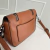 Bolsa pequena de couro marrom com duas alças e detalhes em corrente prateada.
