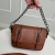 Bolsa pequena de couro marrom com duas alças e detalhes em corrente prateada.