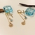Brinco Argola Articulada 1mm c/ Pêndulos em Filetes Pingentes Crucifixo/Olho Grego/São Bento banho ouro 18k (ARG1418)