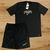 Conjunto masculino da Nike composto por uma camisa preta e um short, ambos com detalhes em branco.