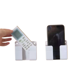 Suporte para controle remoto e celular, na cor branca, com controle remoto sendo colocado e celular em exibição.