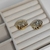 Brinco croissant folheado a ouro 18k, com design ondulado, apresentado em uma superfície de veludo claro.