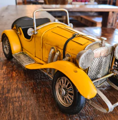 Carro conversível de metal amarelo, perfeito para adicionar sofisticação e charme à decoração de qualquer ambiente.