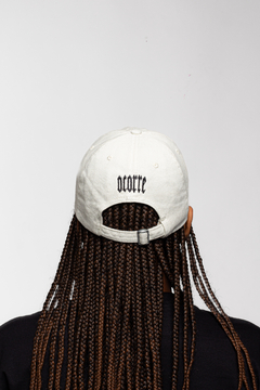 Boné Dad Hat A.C.R na cor Off White, visto de trás, com o logo "OCORRE" bordado.