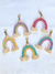 Chaveiros de macramê em forma de arco-íris com franjas, em cores variadas.