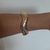 Bracelete dourado ondulado banhado à ouro em um braço.