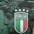 Emblema da camisa da seleção italiana com três estrelas, representando conquistas, sobre um fundo verde com detalhes artísticos.