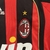 Camisa de time infantil do AC Milan 2006/07 com listras vermelhas e pretas, logo da Adidas e estampa "bwin".