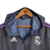Jaqueta corta-vento preta do Real Madrid com detalhes em roxo e logo da Adidas.