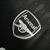 Emblema da camisa do goleiro do Arsenal 2023/24, destacando o logo em preto e branco.