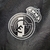 Corta-vento preta do Real Madrid, com capuz e logo da Adidas, pendurada em um cabide.