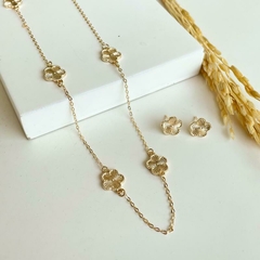 Conjunto de joias douradas com colar e brincos em formato de flor.